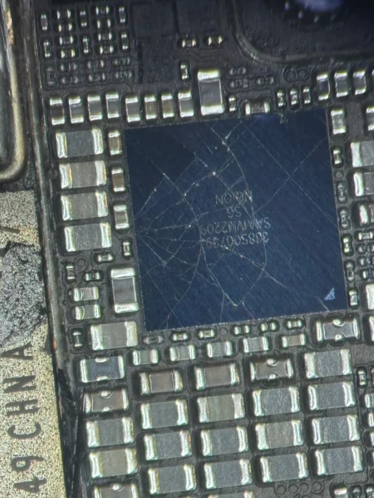 Microscope close-up of surface damage on a chip surrounded by small board components
